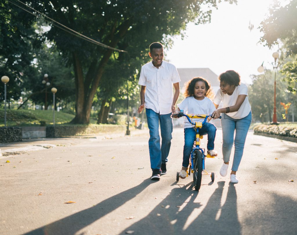 Happy parents with child riding bike outside