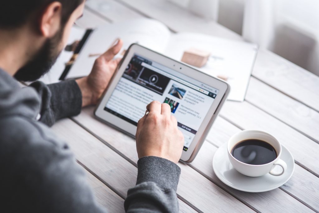 man reading news at table with coffee