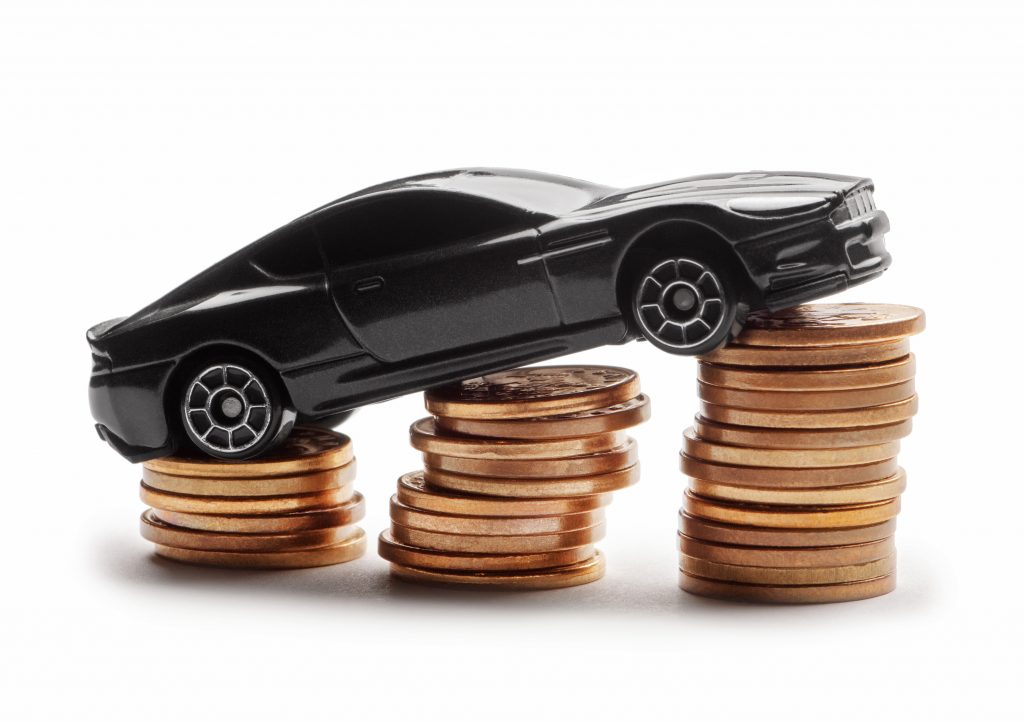Car model over a lot of money stacked coins on white background